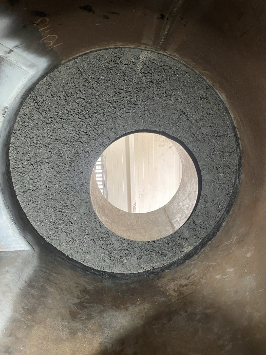 Refractory lining inside a circular boiler shell with a central opening.