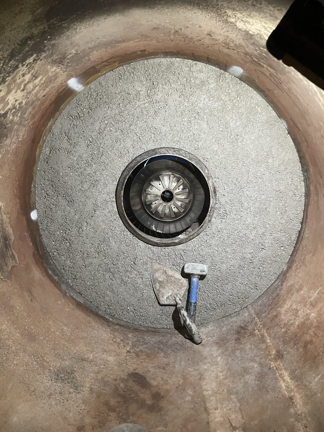 Circular refractory lining and burner head with tools beside the opening.
